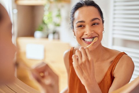 Woman smiling while brushing her teeth