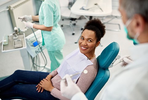 Woman in treatment chair smiling at dentist