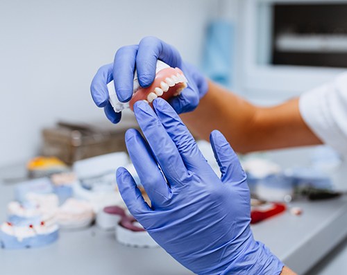 A closeup of gloved hands holding a denture