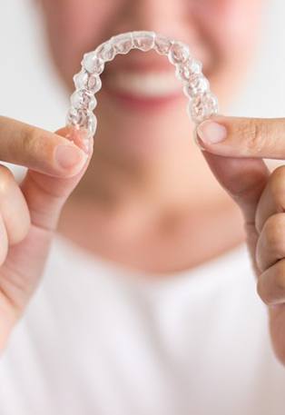 closeup of patient holding Invisalign clear aligner