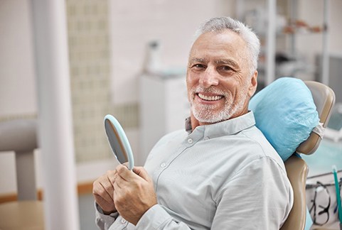Man at dentist’s office with handheld mirror